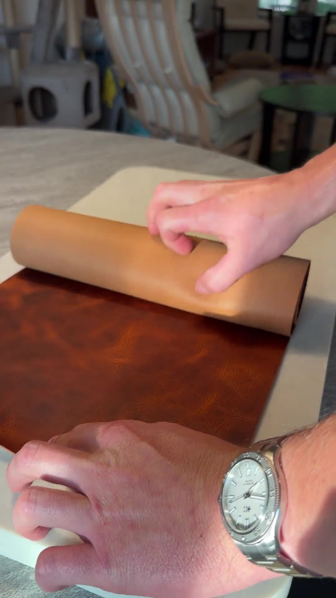 A hand unrolling a sheet of full-grain leather